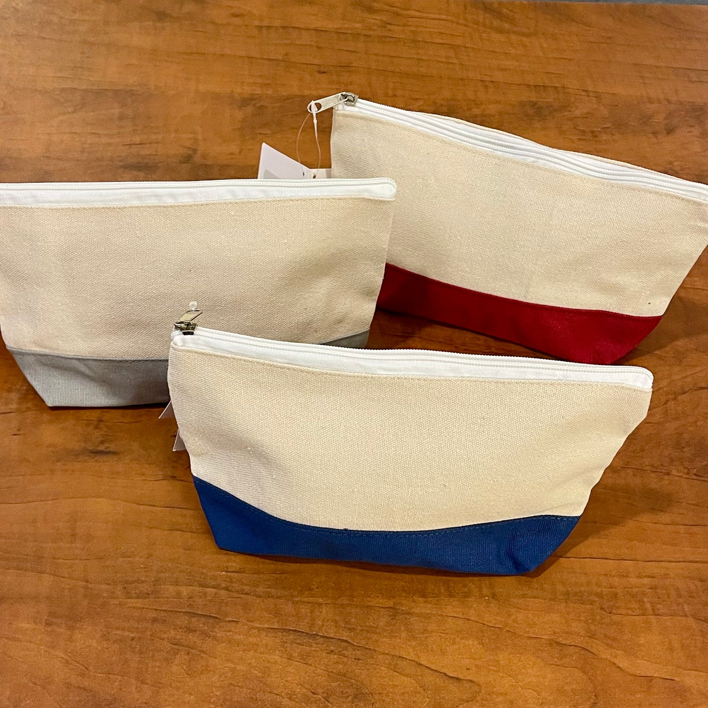 Three fabric pouches with zipper closures on a wooden surface