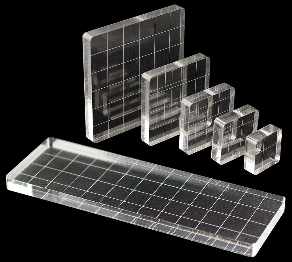 Introducing the faire Acrylic Block Stamp Set, a 6-piece collection designed for precision stamping. The set features clear acrylic blocks with grid lines, displayed against a black background. It includes a large rectangular block and several smaller square blocks, each incrementally decreasing in size for versatile use with silicone stamps.