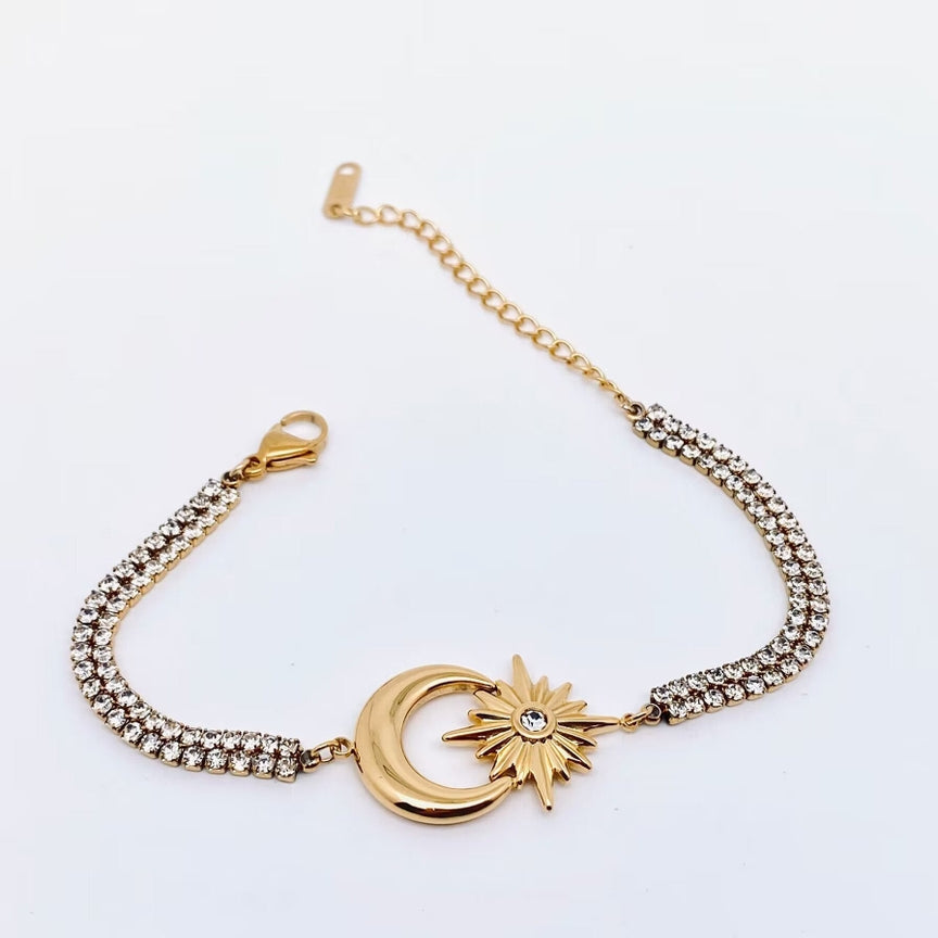 The 18k gold-plated Star Moon charm cubic zirconia bracelet by faire showcases a central crescent moon and star design, embellished with cubic zirconia on both sides. It features a lobster clasp and an adjustable chain, all set against a white background.