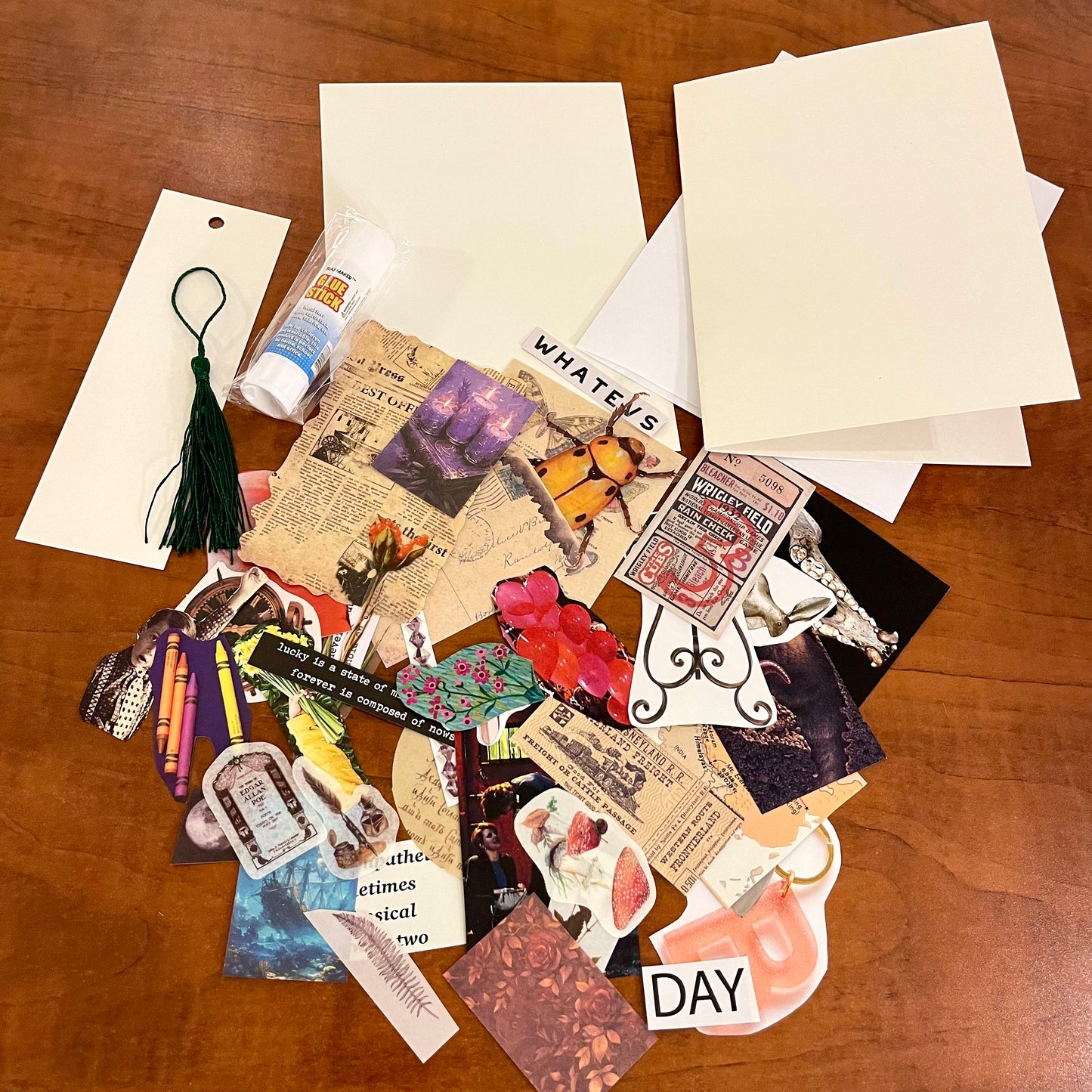 Collection of vintage-style cards, stickers, and a tassel on a wooden surface.