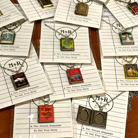 a collection of locket necklaces that feature book covers like A Court of Thorns and Roses.