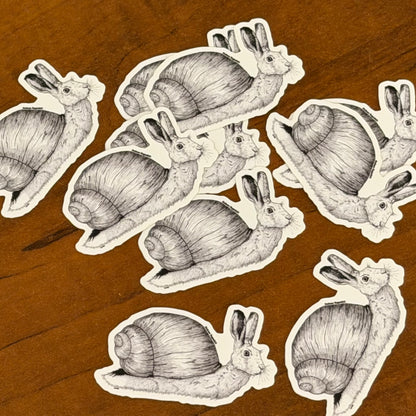 Illustrations of snail rabbits as stickers on a wooden surface