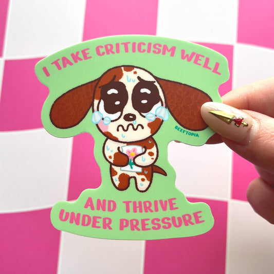 Sticker with a dog illustration and text held by a hand on a pink and white checkered background