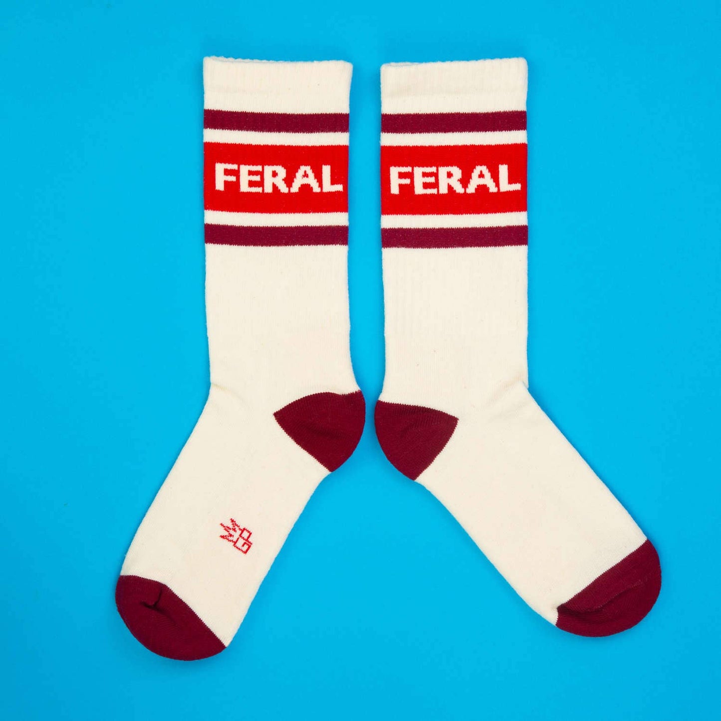 White socks with red and maroon accents and 'FERAL' branding on a blue background
