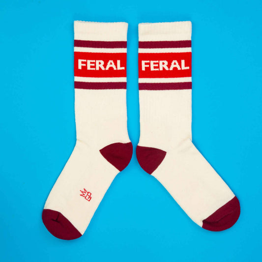 White socks with red and maroon accents and 'FERAL' branding on a blue background