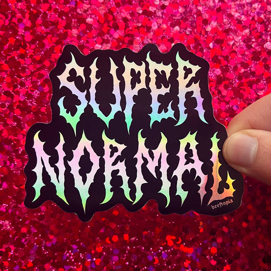 Sticker with 'Slightly Normal' text held over a red glittery background