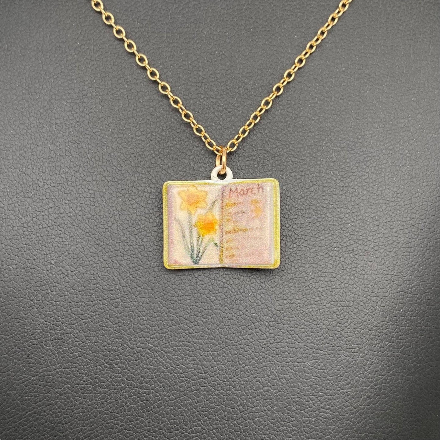 Necklace with a pendant featuring an open book with flowers on a gray background