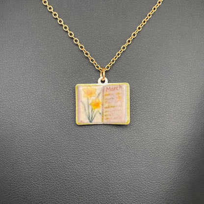 Necklace with a pendant featuring an open book with flowers on a gray background