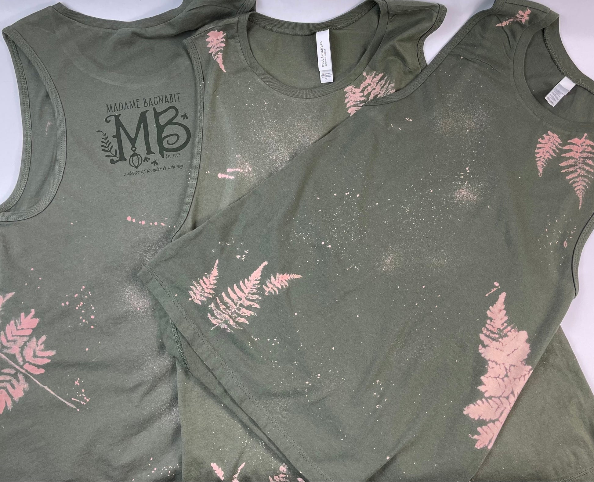 Two green tank tops with pink fern designs on a white background