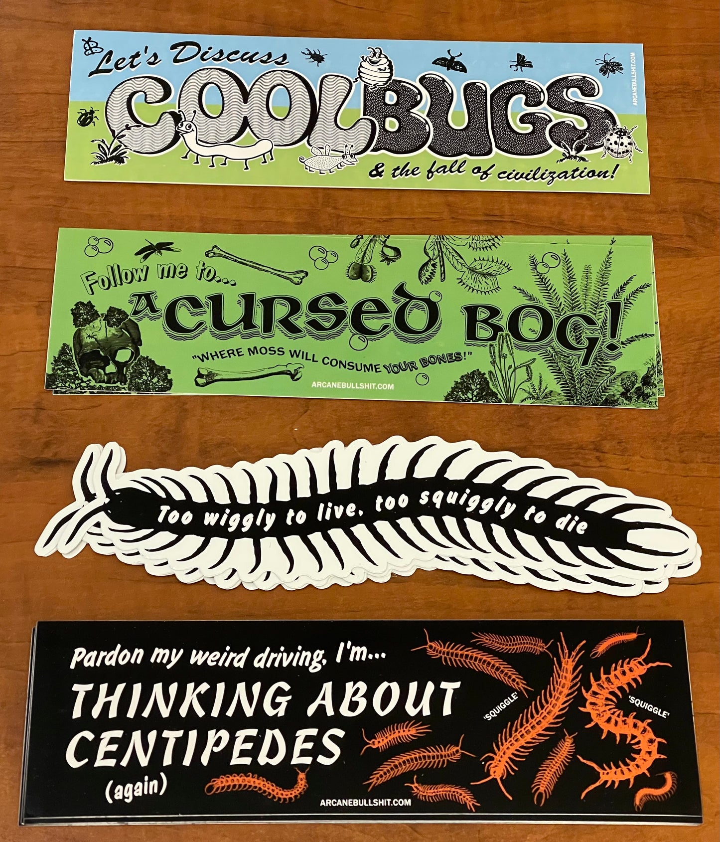 Four stickers with humorous text and graphics on a wooden surface