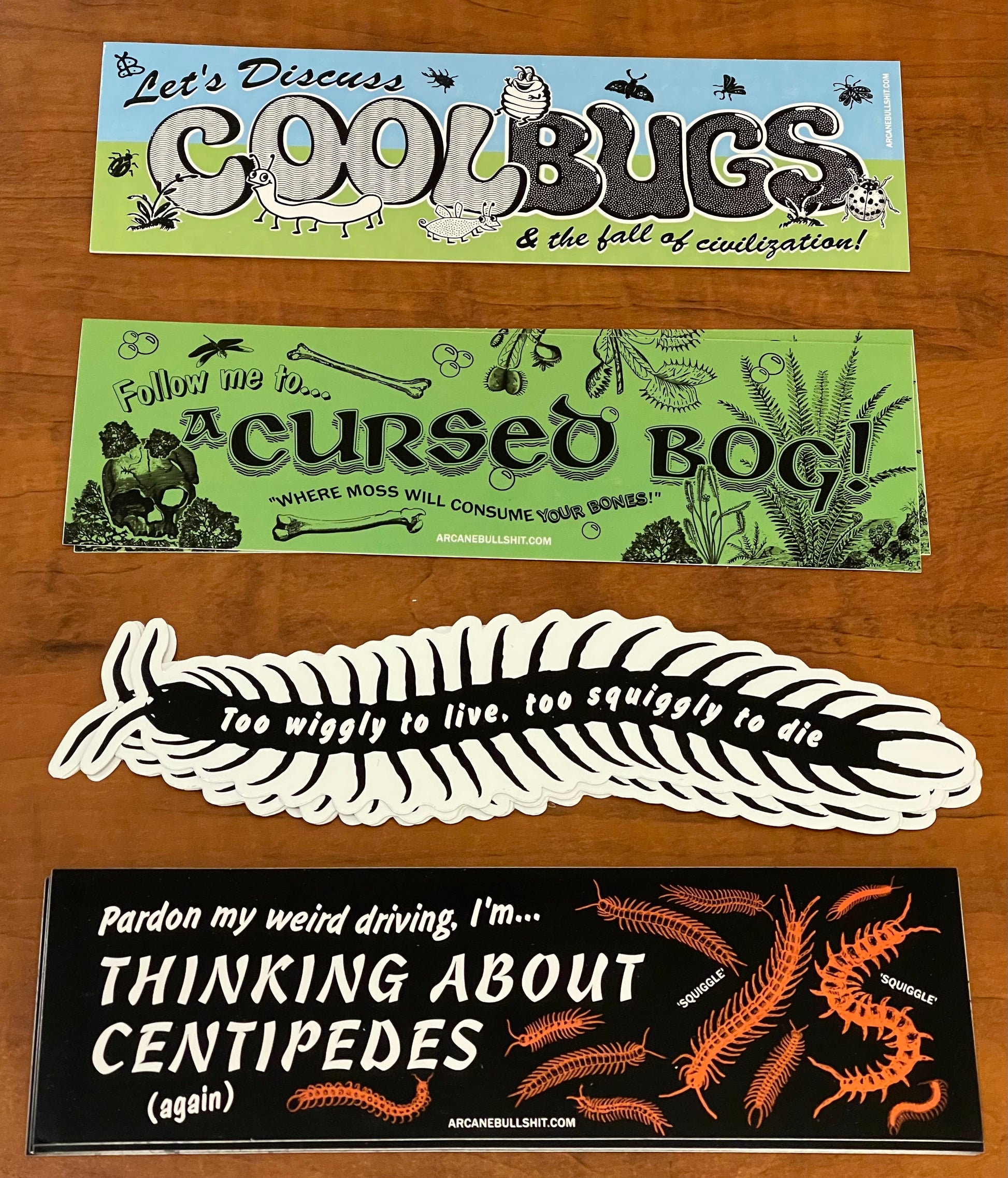 Four stickers with humorous text and graphics on a wooden surface