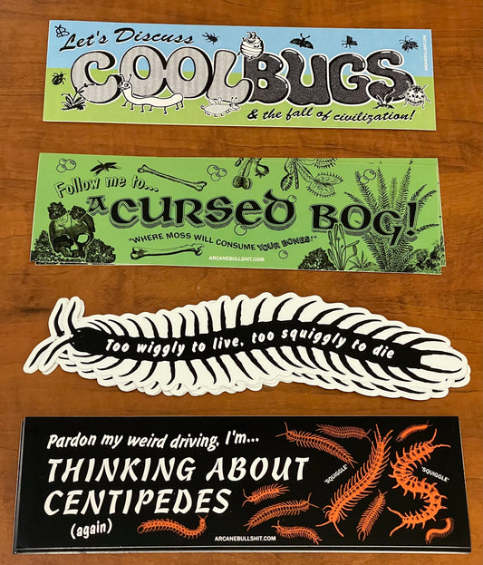 Four stickers with humorous text and graphics on a wooden surface