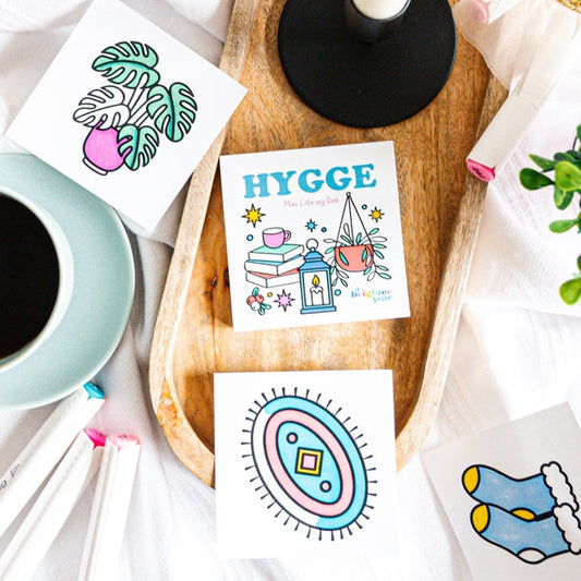 Colorful cards with illustrations on a wooden tray with a candle