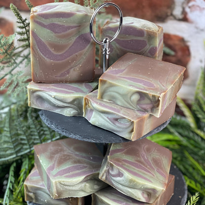 Stack of marbled soap bars on a tiered stand with greenery in the background