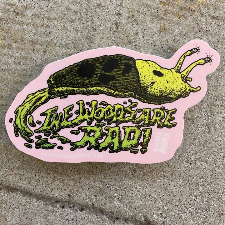 Sticker with a slug illustration and text 'The Woods Are Rad!' on a concrete surface