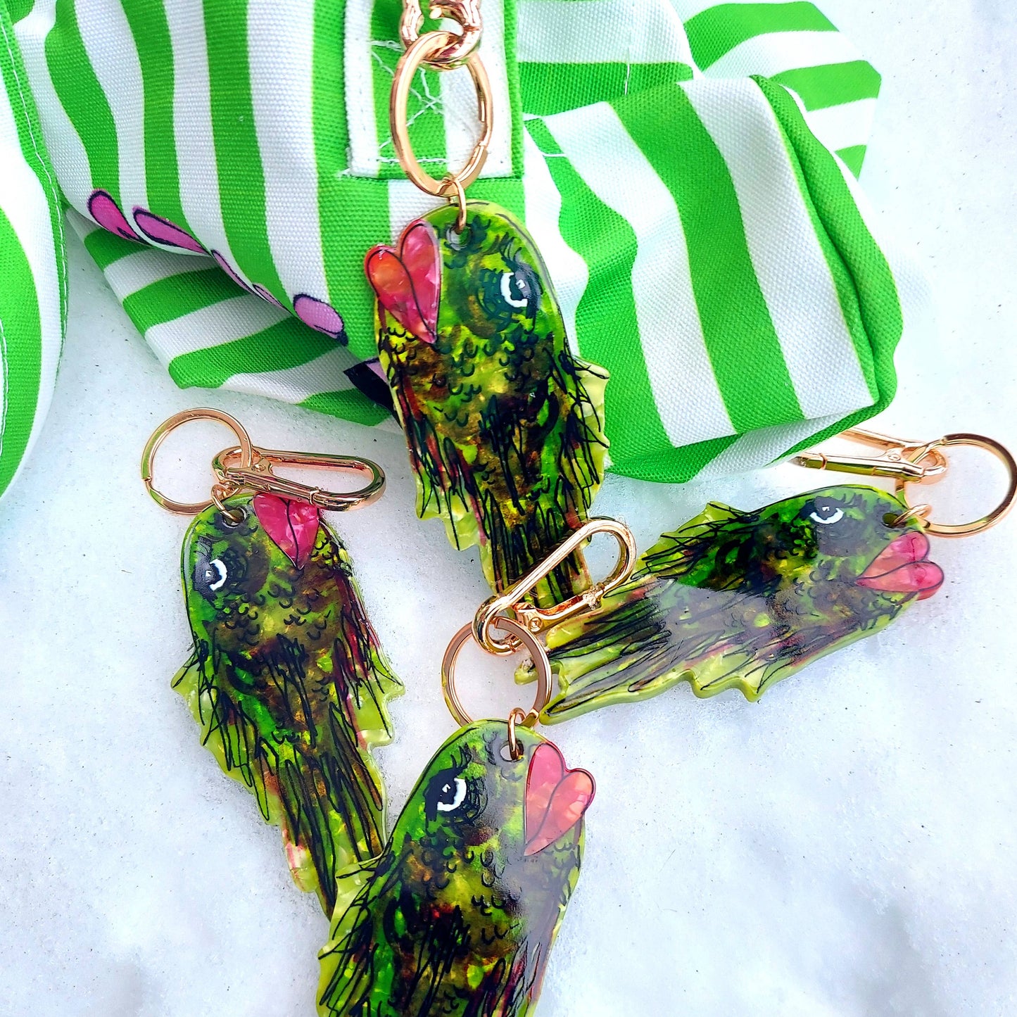 Green fish-shaped keychains with pink accents on a white background