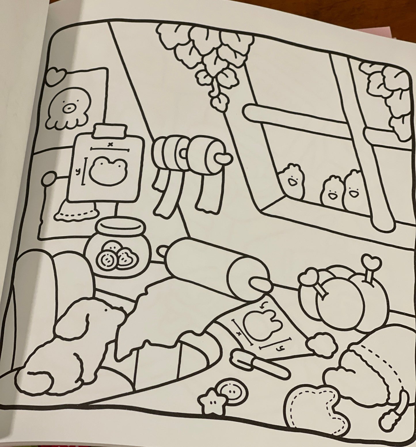 Coloring book page with a cartoon character and various objects on a wooden surface.