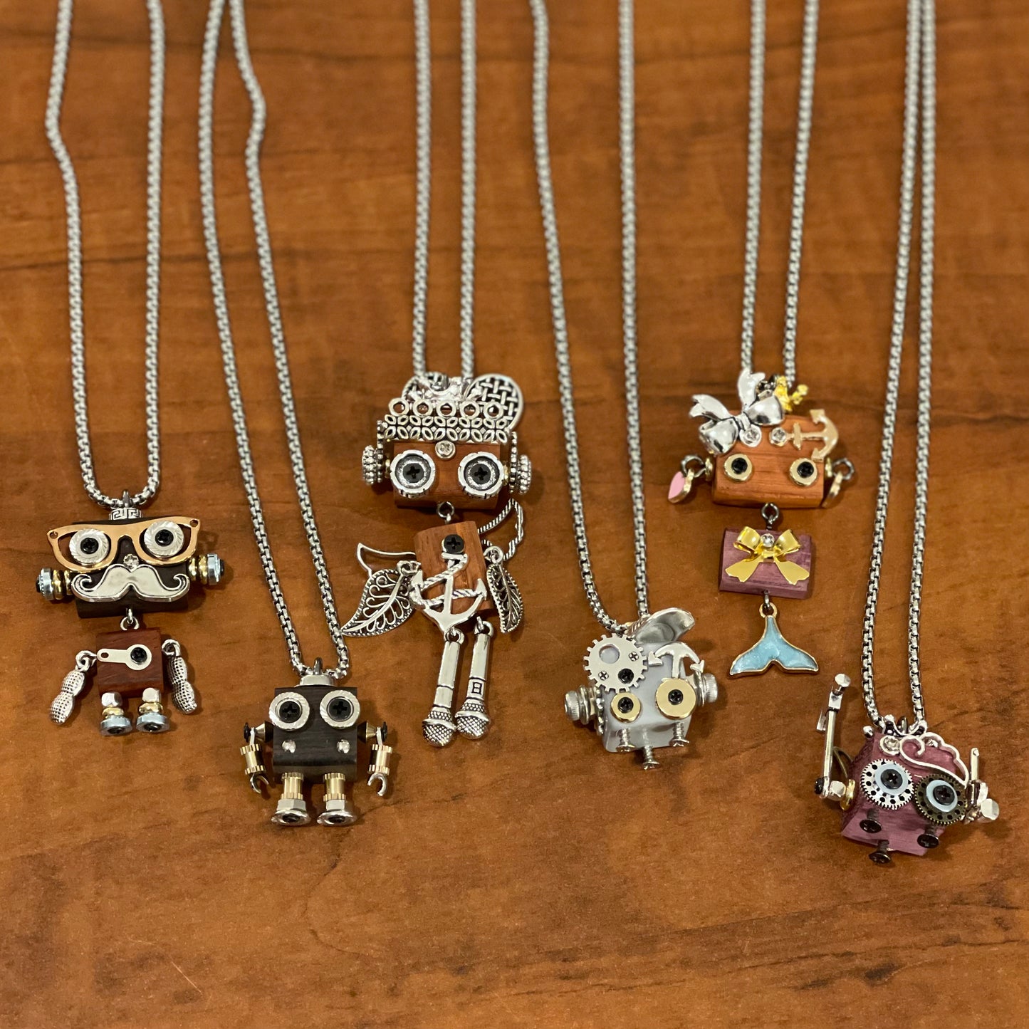 Collection of unique necklaces with various robot pendants on a wooden surface