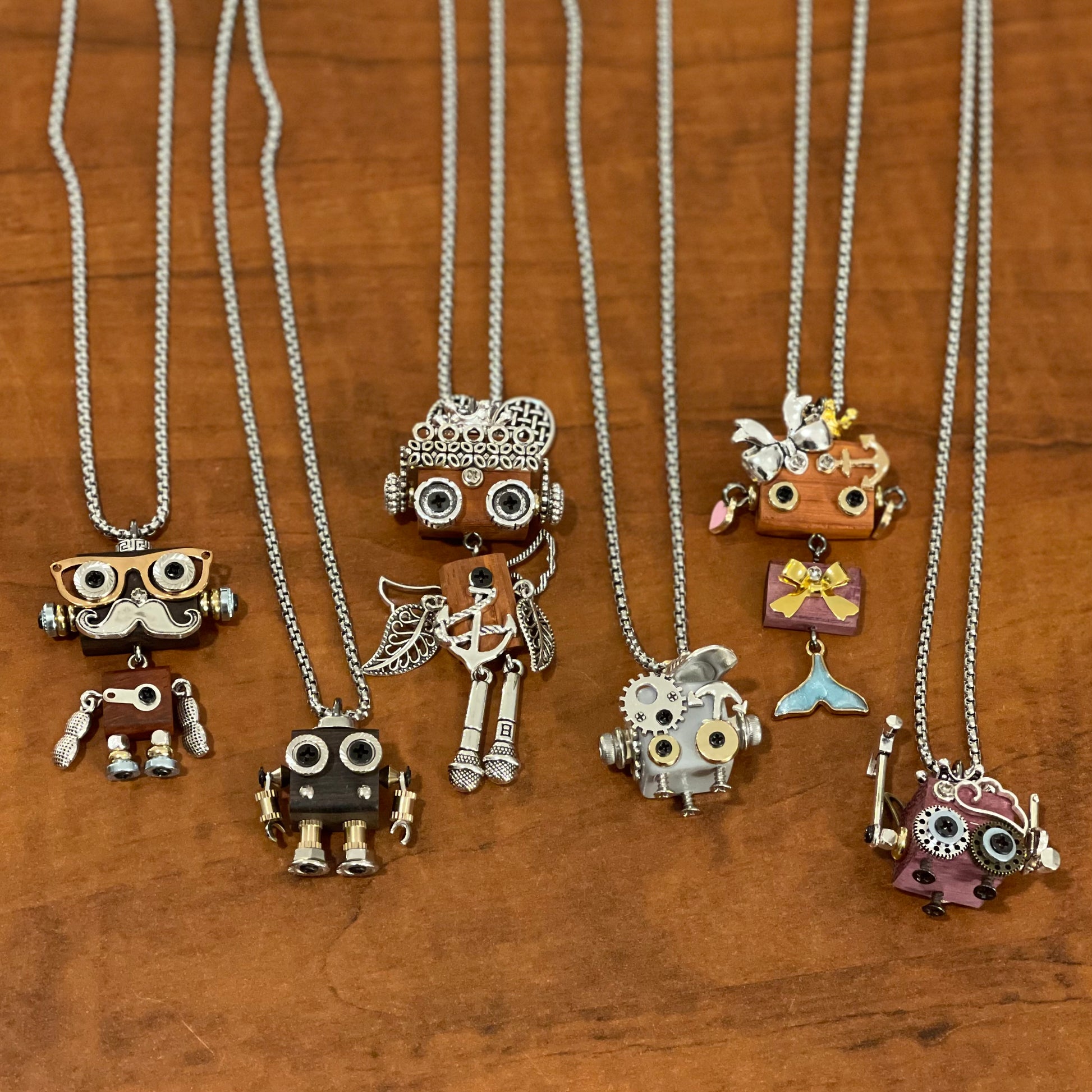 Collection of unique necklaces with various robot pendants on a wooden surface