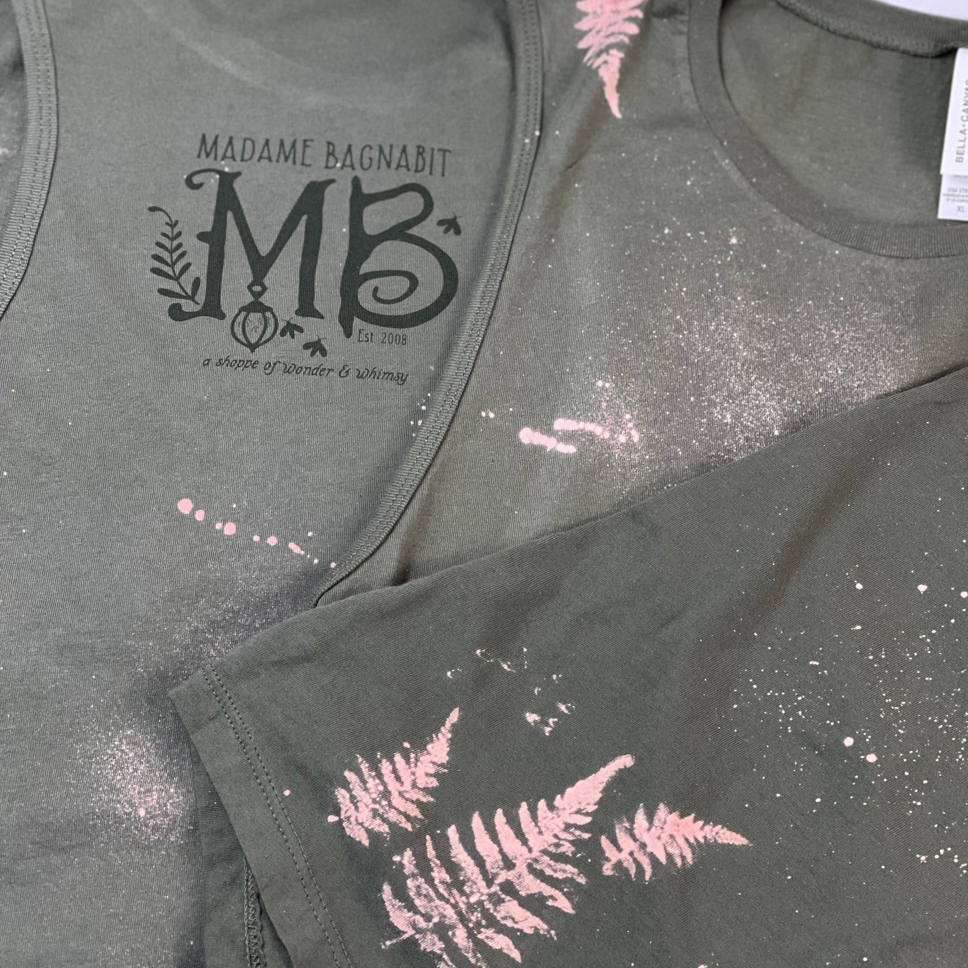 Two green tank tops with decorative prints on a light gray background