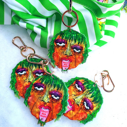 Colorful earrings with face designs on a green and white striped fabric background