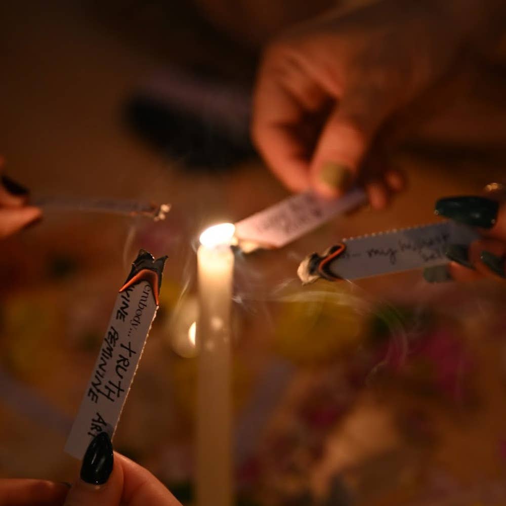 Candle being lit with a match, surrounded by small notes and flowers on a blurred background