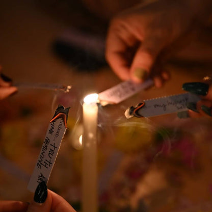 Candle being lit with a match, surrounded by small notes and flowers on a blurred background